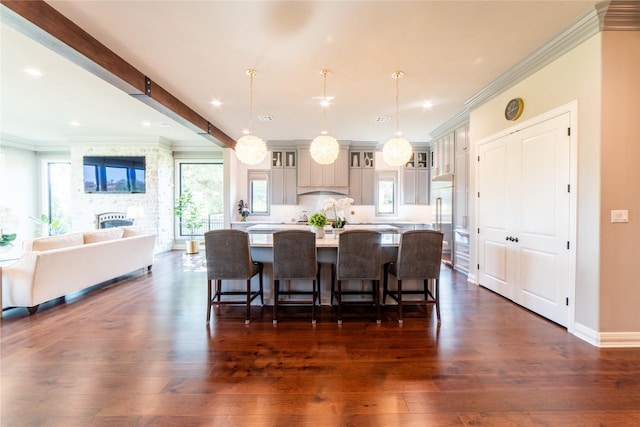 dining room with a stone fireplace, crown molding, beamed ceiling, and dark wood-type flooring