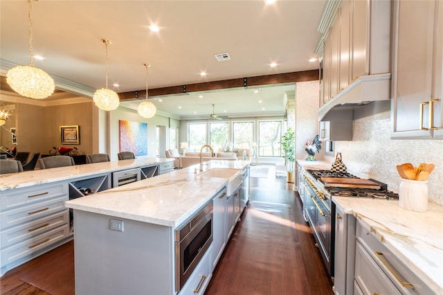 kitchen with stainless steel microwave, a spacious island, sink, hanging light fixtures, and decorative backsplash