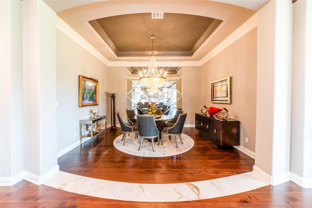 dining area with a tray ceiling, an inviting chandelier, dark hardwood / wood-style floors, and crown molding