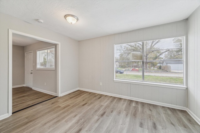 unfurnished room featuring a textured ceiling and light hardwood / wood-style flooring