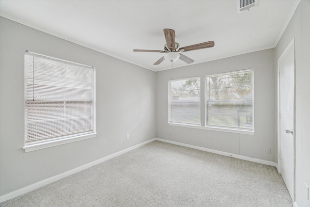 spare room with ceiling fan, light colored carpet, and crown molding