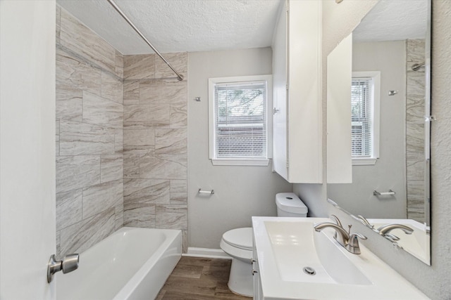 full bathroom featuring hardwood / wood-style floors, a textured ceiling, toilet, and tiled shower / bath combo