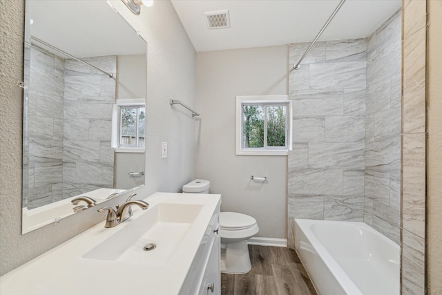 full bathroom with hardwood / wood-style floors, vanity, toilet, and tiled shower / bath