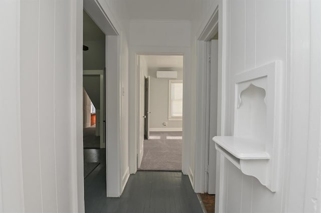 corridor with an AC wall unit, dark carpet, and ornamental molding