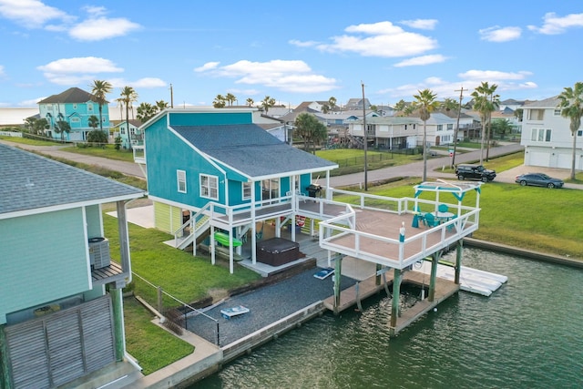 back of house featuring a lawn, a deck with water view, a jacuzzi, and central AC