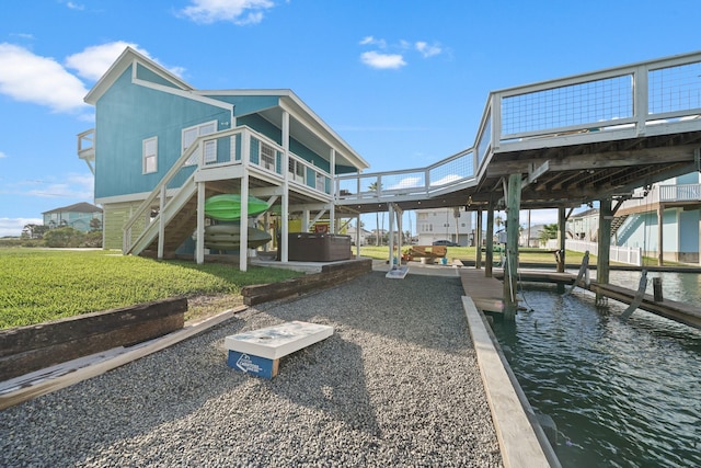 exterior space featuring a yard, a water view, and a hot tub