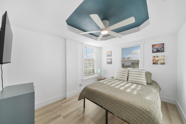 bedroom with multiple windows, a raised ceiling, and ceiling fan