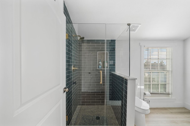 bathroom with wood-type flooring, toilet, and an enclosed shower