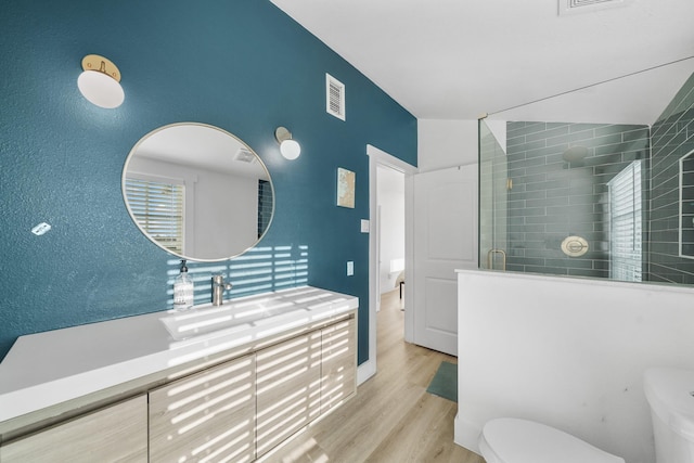 bathroom featuring vanity, wood-type flooring, lofted ceiling, toilet, and a shower with shower door