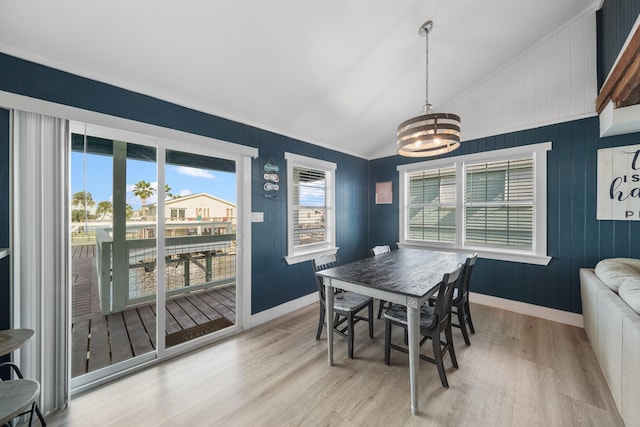 dining area featuring a chandelier, light hardwood / wood-style floors, and vaulted ceiling