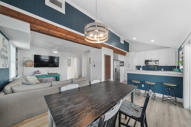 dining area featuring ceiling fan with notable chandelier, light wood-type flooring, and lofted ceiling