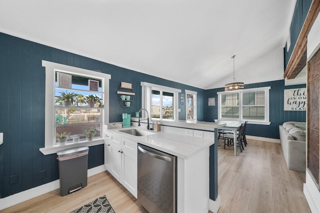 kitchen with kitchen peninsula, stainless steel dishwasher, sink, decorative light fixtures, and white cabinets