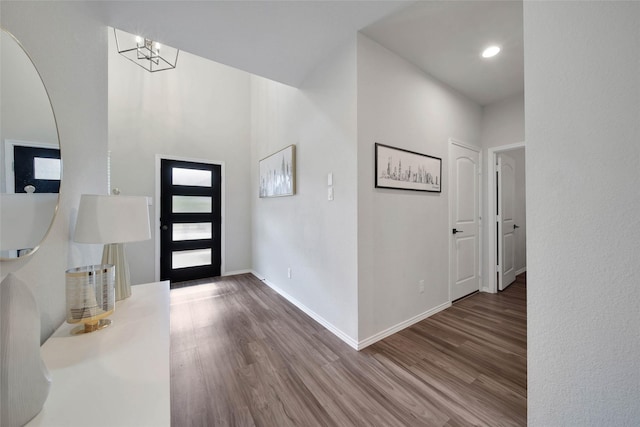 entryway with a towering ceiling, a chandelier, and hardwood / wood-style flooring