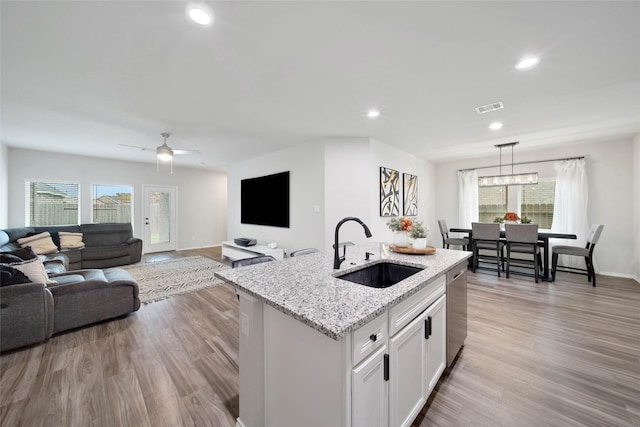 kitchen featuring white cabinets, a center island with sink, sink, decorative light fixtures, and stainless steel dishwasher