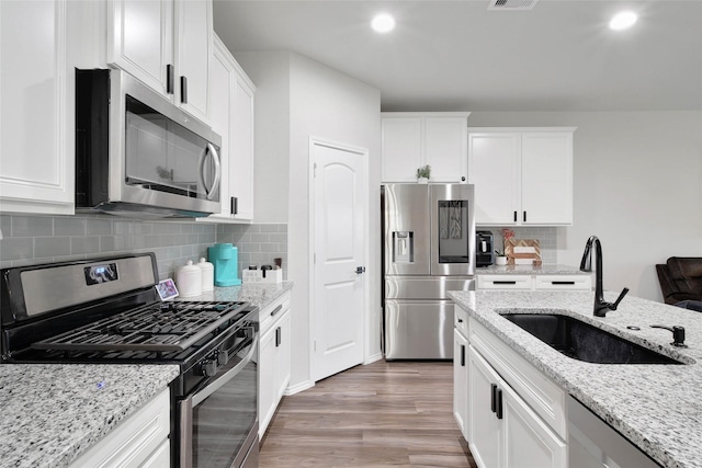 kitchen with stainless steel appliances, white cabinetry, decorative backsplash, and sink