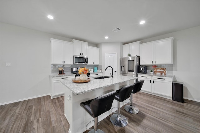 kitchen featuring sink, stainless steel appliances, an island with sink, and white cabinets