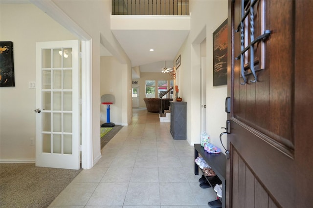 carpeted foyer with lofted ceiling and a notable chandelier