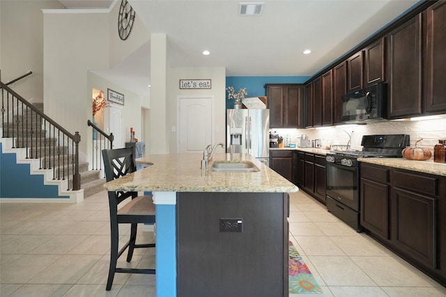 kitchen featuring a kitchen island with sink, sink, light tile patterned floors, and black appliances