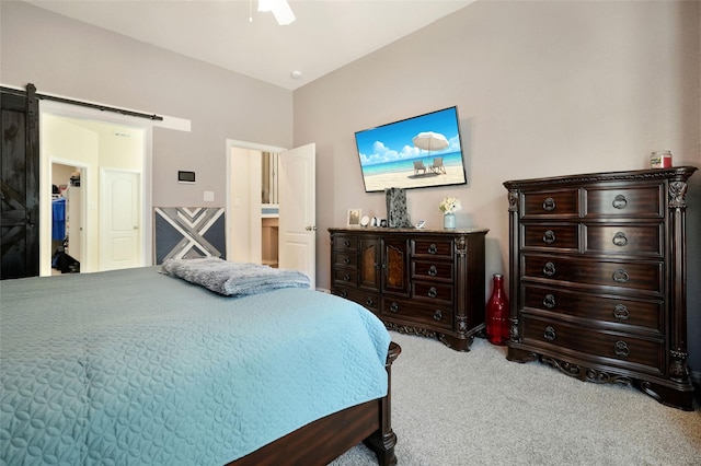 carpeted bedroom with ceiling fan and a barn door