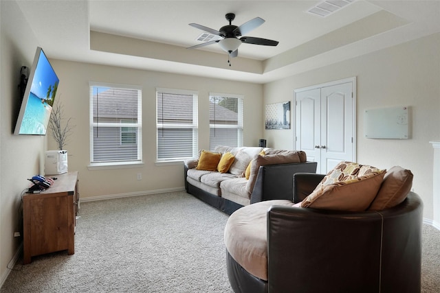 living room featuring carpet floors, a raised ceiling, and ceiling fan