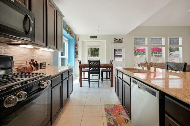 kitchen featuring sink, light stone counters, dark brown cabinets, light tile patterned floors, and black appliances