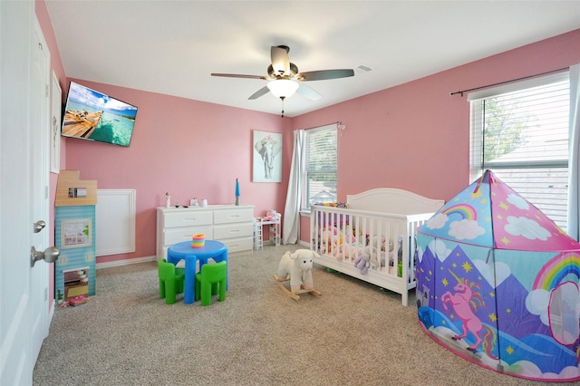 carpeted bedroom with a nursery area and ceiling fan