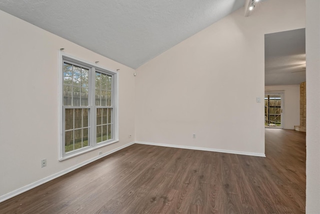 empty room with a textured ceiling, dark wood-type flooring, and vaulted ceiling