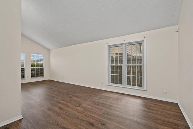 empty room featuring a textured ceiling, dark hardwood / wood-style floors, and lofted ceiling