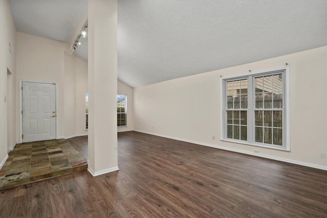 unfurnished living room featuring lofted ceiling, track lighting, and dark wood-type flooring