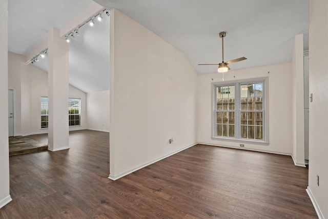 interior space with rail lighting, ceiling fan, dark wood-type flooring, and vaulted ceiling