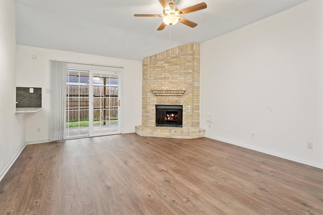 unfurnished living room with ceiling fan, hardwood / wood-style floors, vaulted ceiling, and a brick fireplace