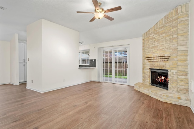 unfurnished living room with ceiling fan, wood-type flooring, lofted ceiling, and a brick fireplace