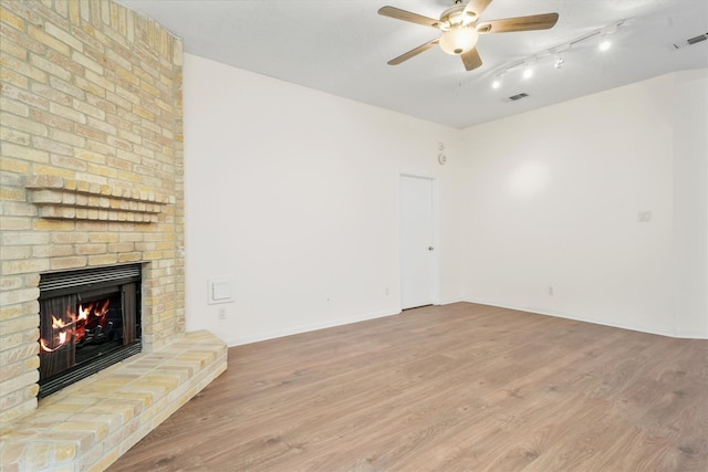 unfurnished living room featuring ceiling fan, light hardwood / wood-style floors, and a brick fireplace