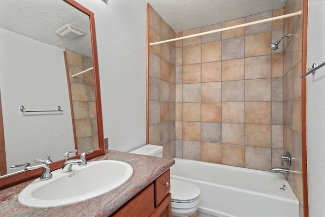 full bathroom featuring vanity, tiled shower / bath, a textured ceiling, and toilet