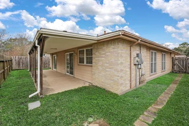 rear view of house featuring a lawn and a patio