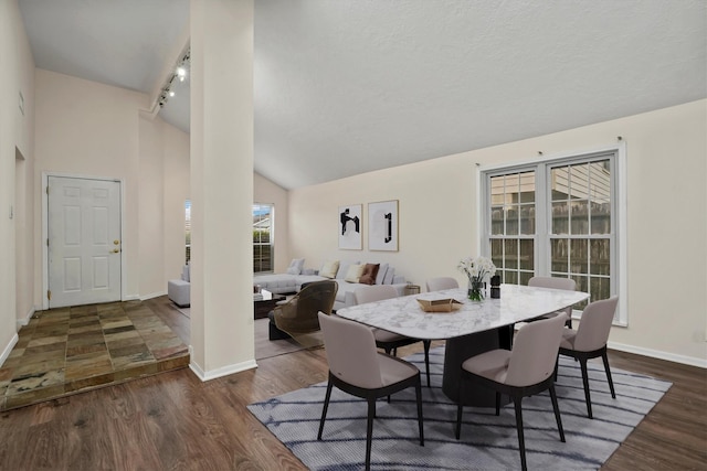 dining area with a textured ceiling, dark hardwood / wood-style flooring, lofted ceiling, and rail lighting