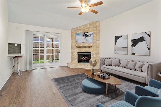 living room featuring ceiling fan, a fireplace, vaulted ceiling, and hardwood / wood-style flooring