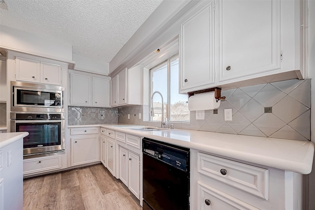 kitchen with white cabinets, light wood-type flooring, appliances with stainless steel finishes, and tasteful backsplash