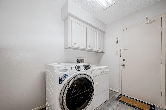 clothes washing area featuring cabinets, a textured ceiling, light hardwood / wood-style flooring, and washer and dryer