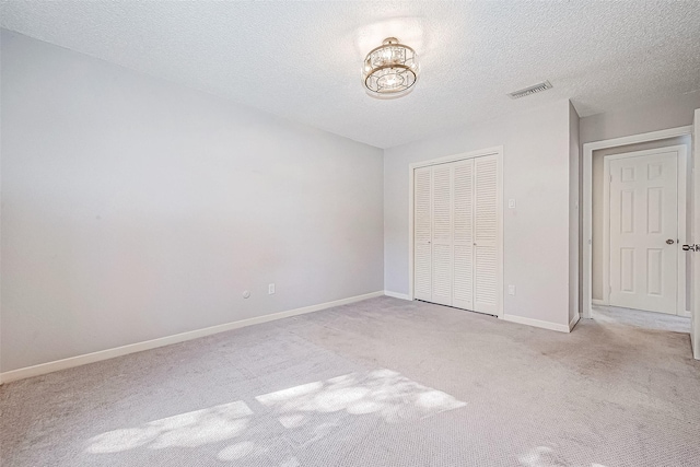 unfurnished bedroom featuring light colored carpet, a textured ceiling, and a closet