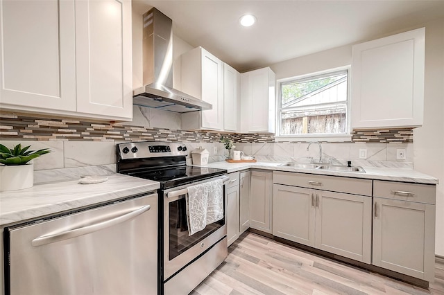 kitchen with white cabinets, sink, wall chimney exhaust hood, and appliances with stainless steel finishes