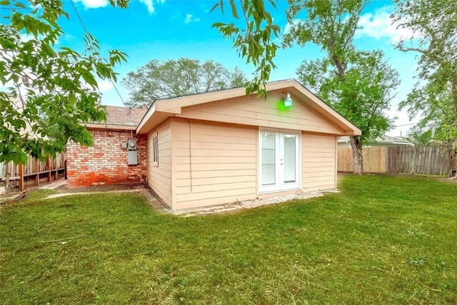 back of house with brick siding, a lawn, and fence