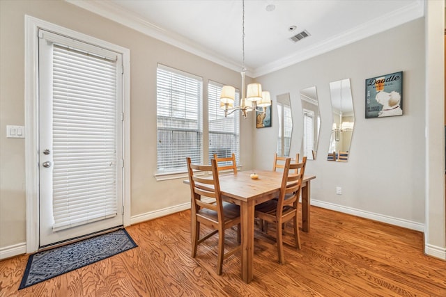 dining area featuring light wood-type flooring, crown molding, and a notable chandelier