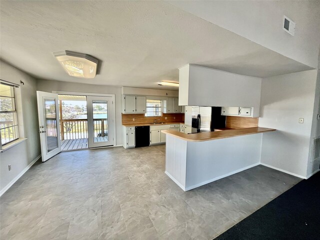 kitchen featuring dishwasher, white cabinetry, kitchen peninsula, and stainless steel refrigerator with ice dispenser