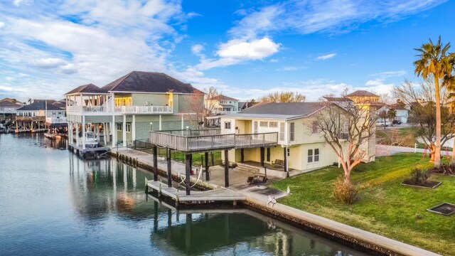 back of house with a lawn, a balcony, and a water view