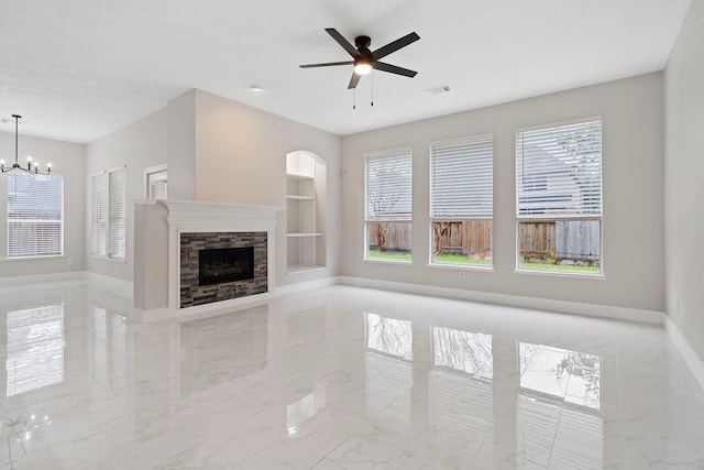 unfurnished living room with ceiling fan with notable chandelier and a fireplace