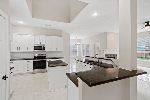 kitchen featuring a center island, kitchen peninsula, sink, white cabinetry, and stainless steel appliances