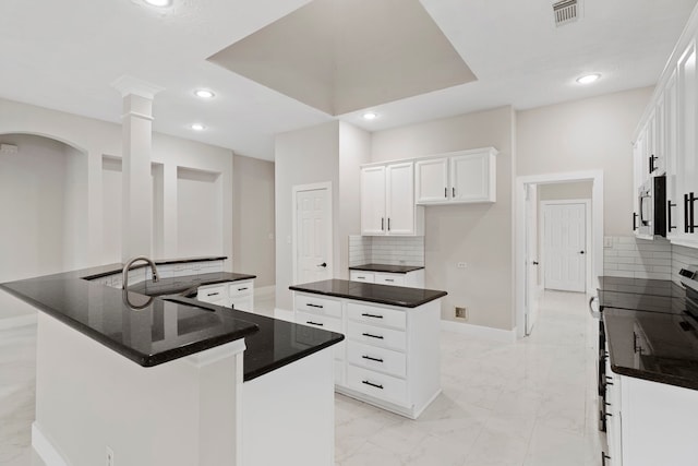 kitchen with white cabinetry, a center island with sink, appliances with stainless steel finishes, decorative backsplash, and sink