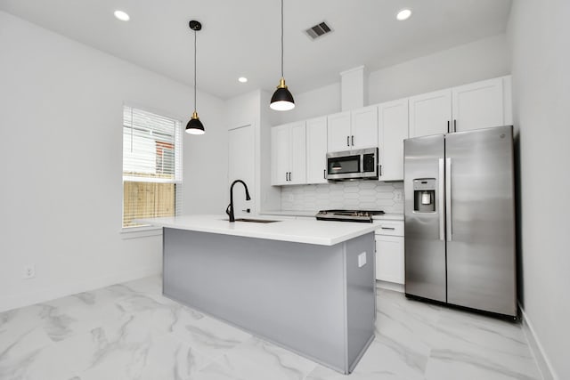 kitchen featuring appliances with stainless steel finishes, white cabinets, a kitchen island with sink, and sink