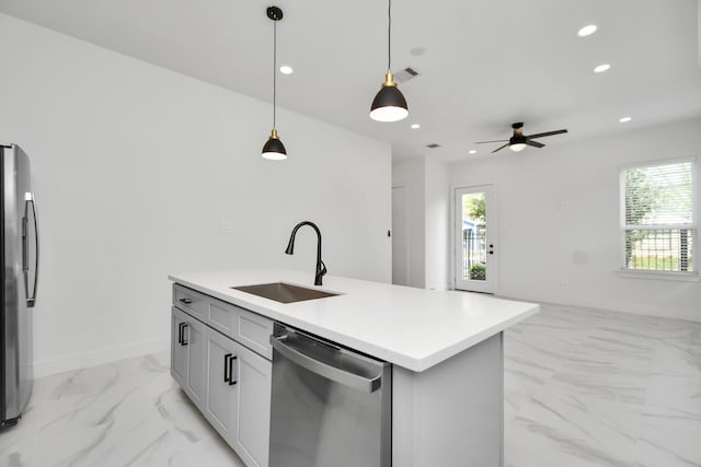 kitchen featuring stainless steel appliances, sink, ceiling fan, an island with sink, and pendant lighting